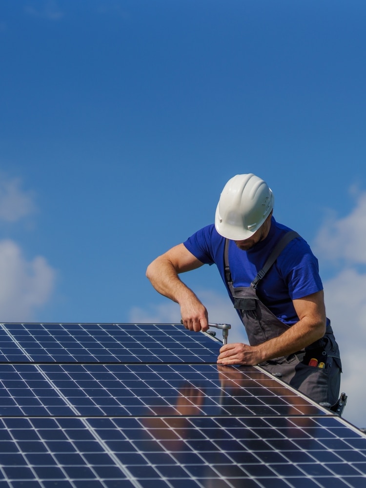 Installation de panneaux solaires par un expert qualifié Technicien installant des panneaux solaires photovoltaïques avec une clé sous un ciel bleu ensoleillé.